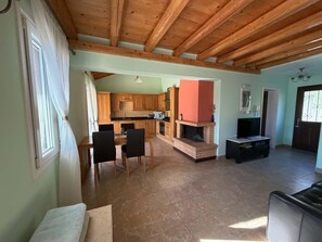 A spacious living area with a fireplace, a dining table with chairs, and a kitchen in the background. - Villa Yason Private Heated Pool Within Easy Reach Of Beaches, Tavernas & Shops. (Ionian Islands)
