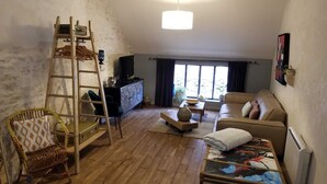 Un accogliente soggiorno in stile loft con un letto a soppalco, un divano, una poltrona e un televisore.