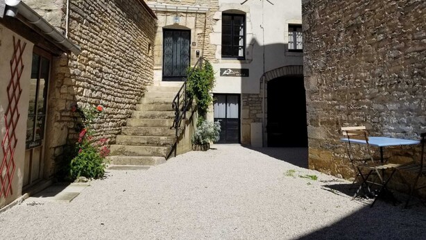 Un strettino vicolo con edifici in pietra, una scala e un tavolo con sedie all'aperto.