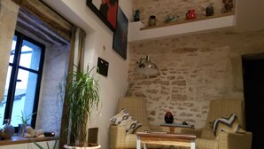 Un soggiorno accogliente con una parete in pietra, due poltrone, un tavolino e una pianta in vaso.