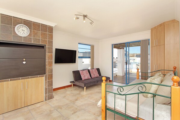 A bedroom with a bed, a sofa, a TV, and a wardrobe. - Oyster Retreat (Langebaan)