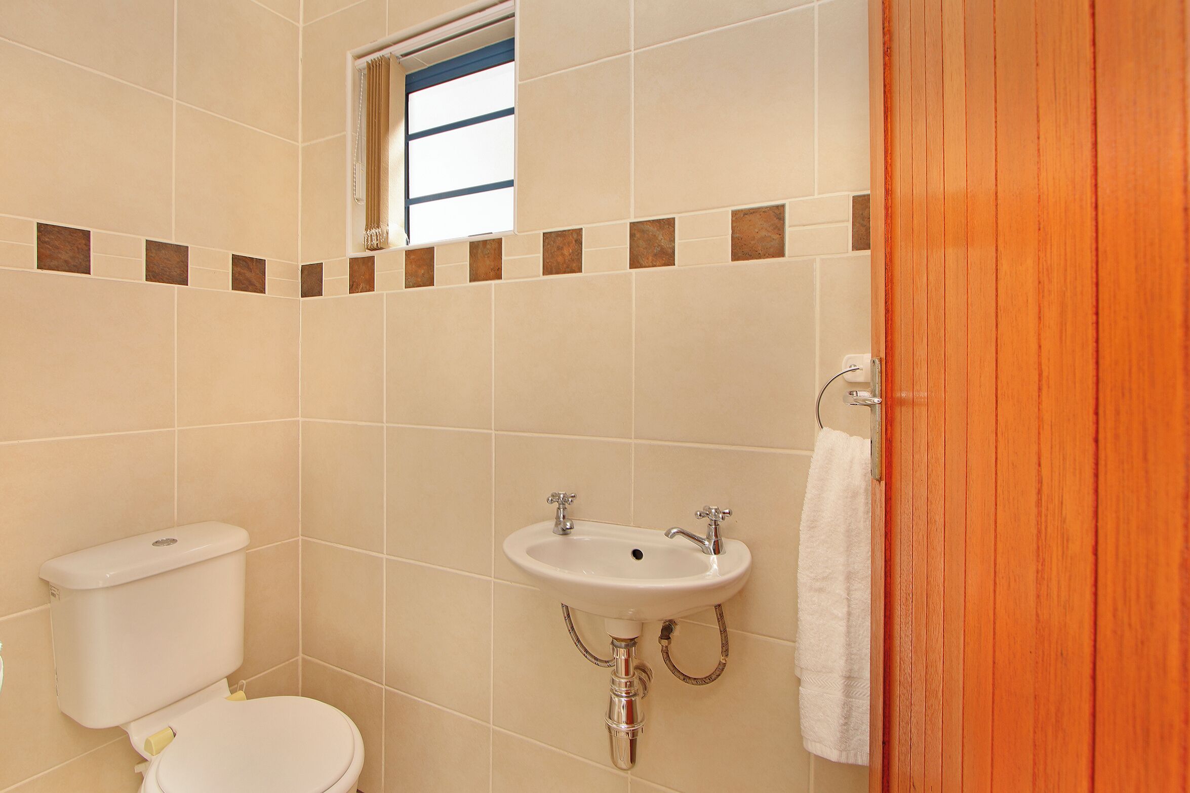 A bathroom with a toilet, sink, and a window.