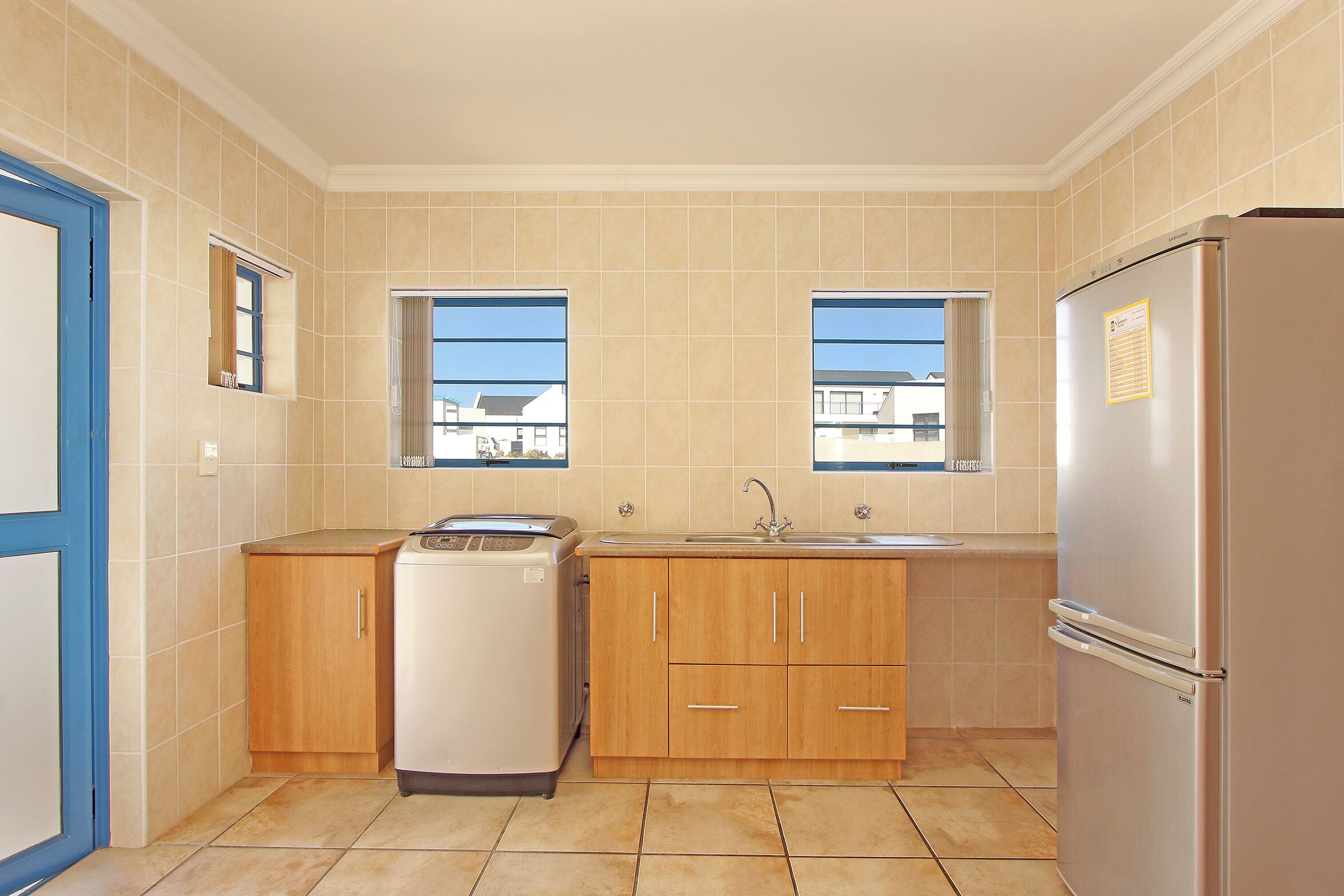 A compact kitchen with wooden cabinets, a built-in oven, a refrigerator, and a window providing natural light.