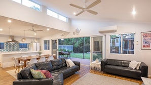 A spacious living area with a black leather sofa, a wooden dining table, and a kitchen with a geometric backsplash. - Tranquility and natural setting a short distance from town and beach (Dunsborough)