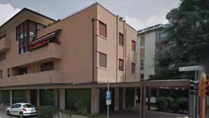 Een meerlaags gebouw met een platte gevel, een overdekte ingang en een parkeerplaats.