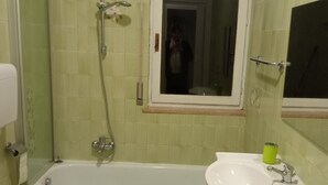 Een badkamer met bad, toilet en wastafel.