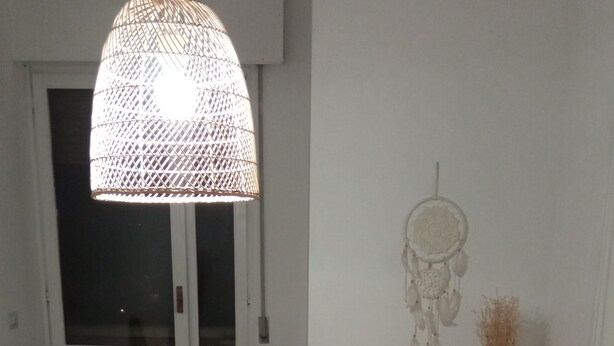 Een kamer met een geweven lamp, een dromenvanger en een rieten kast.
