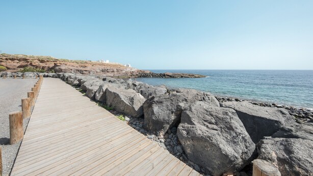 Une promenade en bois qui mène à une côte rocheuse et offre une vue dégagée sur la mer.
