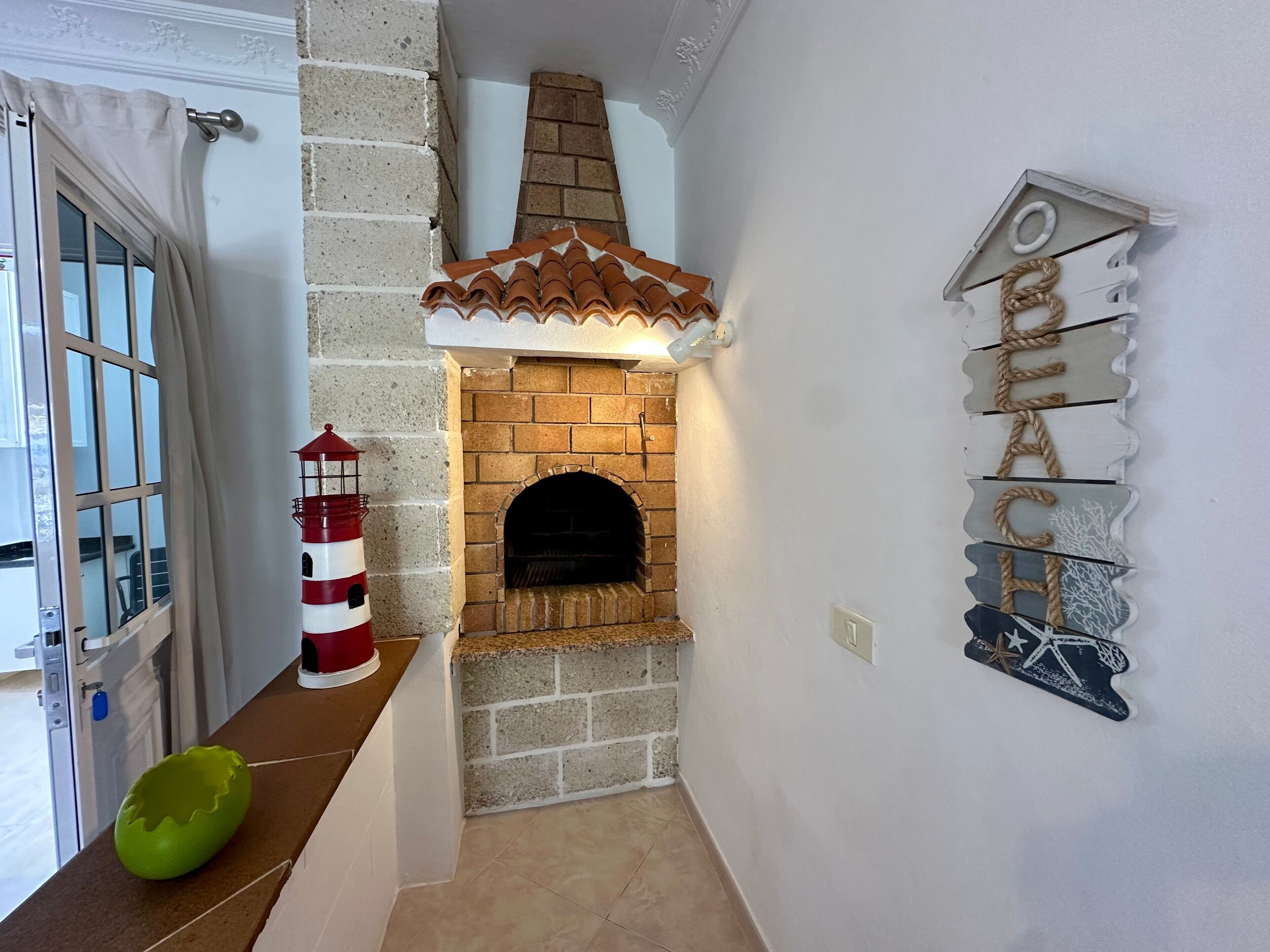 Una cocina con chimenea de ladrillo, una decoración con faro y un letrero en la pared.