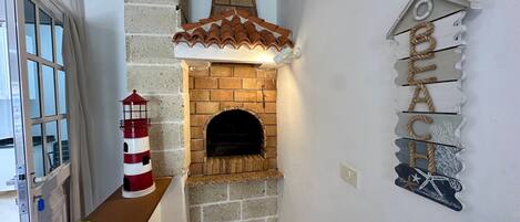 Una cocina con chimenea de ladrillo, una decoración con faro y un letrero en la pared.
