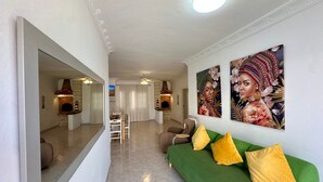 Un salon moderne avec un canapé vert, des coussins jaunes, une cheminée et des œuvres d’art accrochées au mur.
