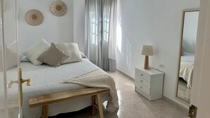 Une chambre à coucher avec un lit, une table de chevet, une lampe et un miroir.