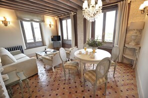 A dining area with a round table, chairs, and a chandelier. There is a sofa and a television in the background. - La Corrala del Realejo (Granada)
