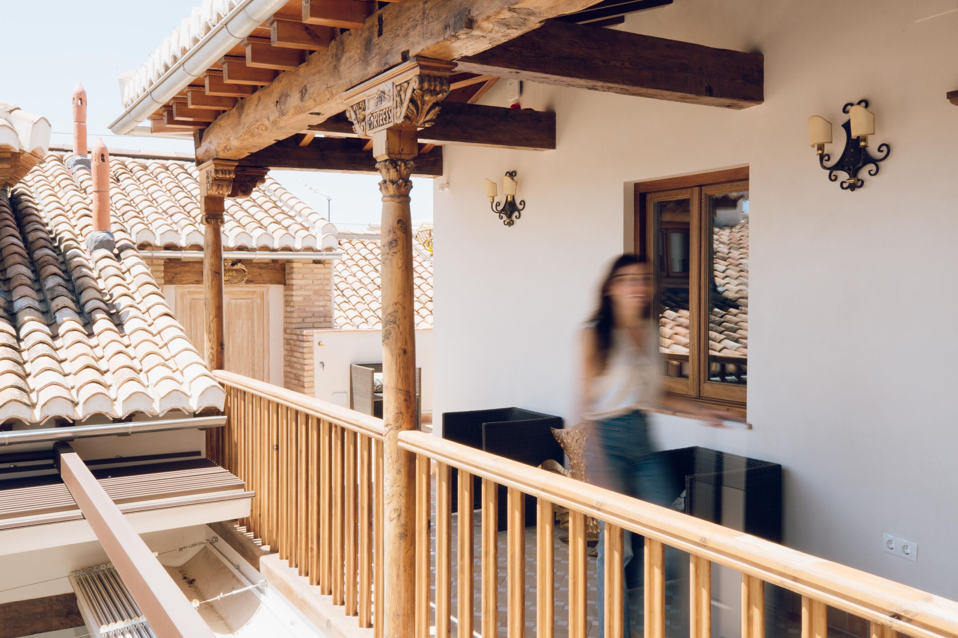 Una escalera con barandillas de madera que lleva a un balcón con techo de tejas.