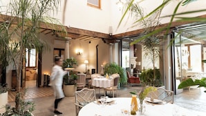 Un comedor con mesas redondas, sillas y plantas en macetas.