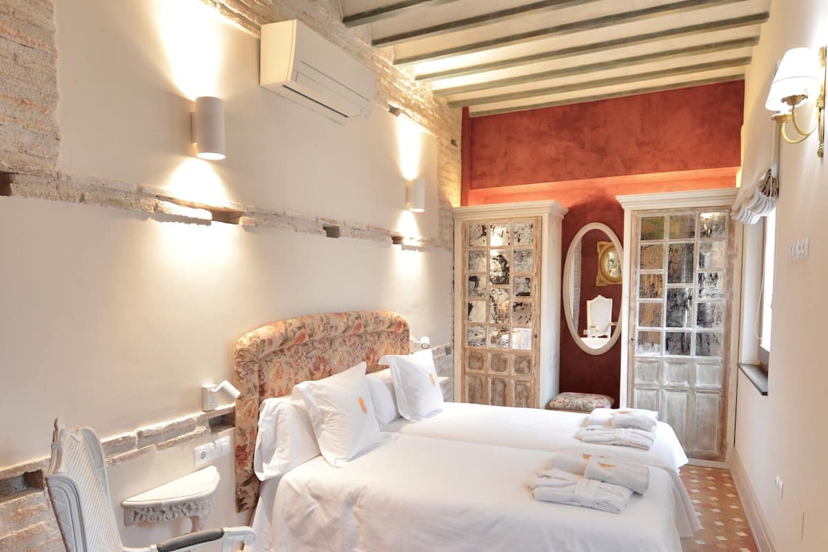 Ein Hotelzimmer mit Bett, einem Sessel, einem kleinen Tisch und einer Tür zu einem Badezimmer.