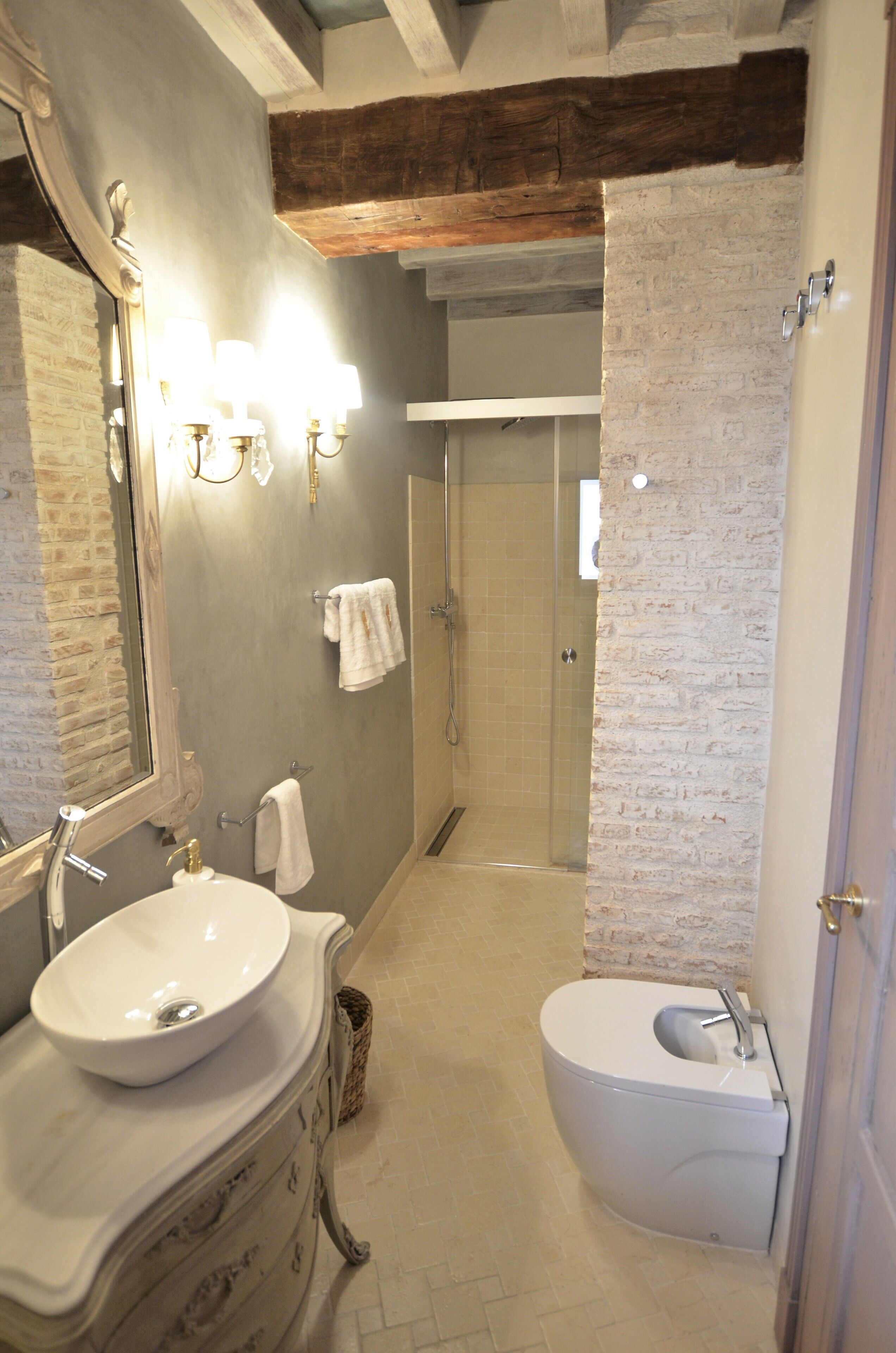 Une salle de bain avec un grand miroir, un lavabo, des toilettes et une douche.