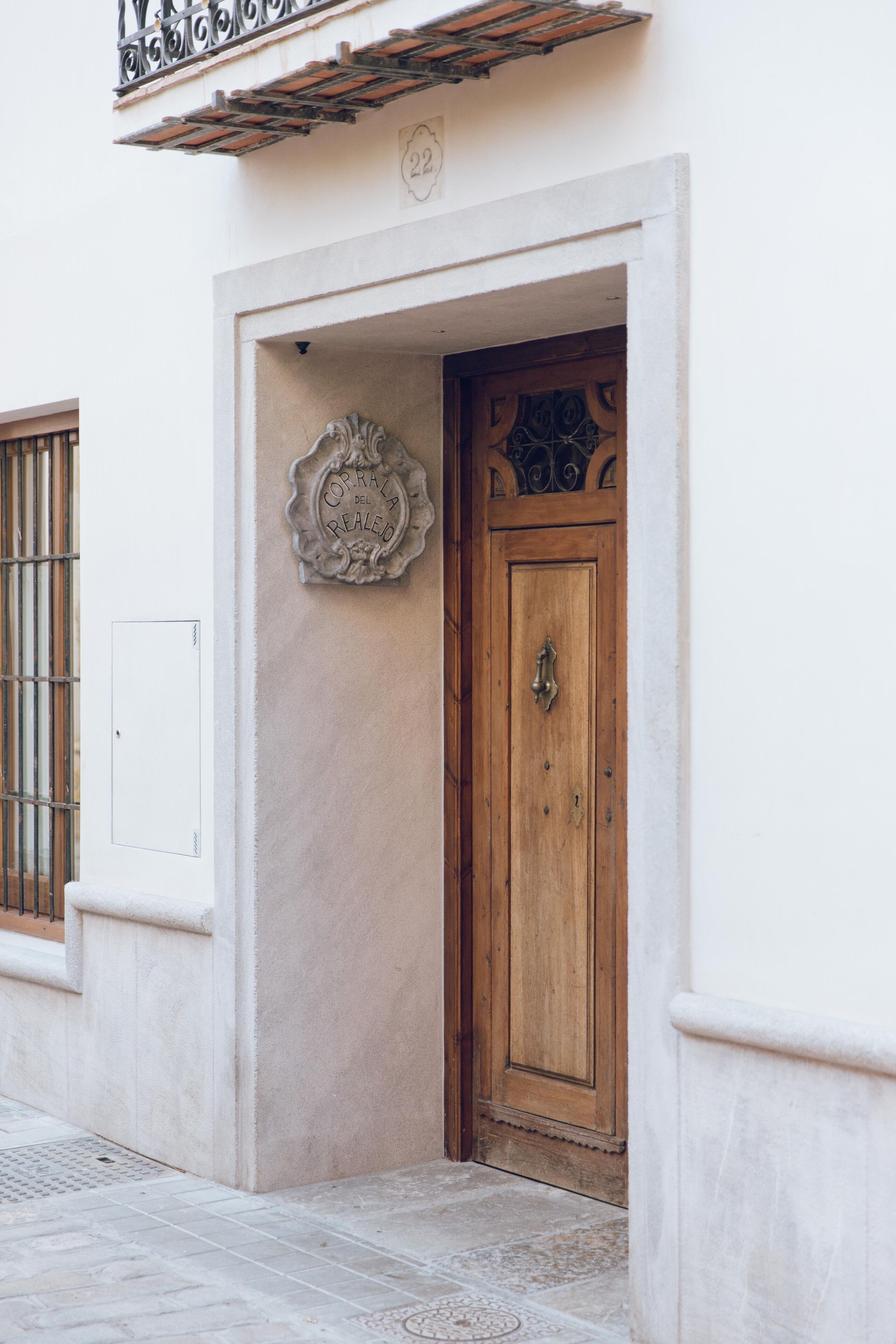 A building entrance with a wooden door, a metal gate, and a decorative plaque.