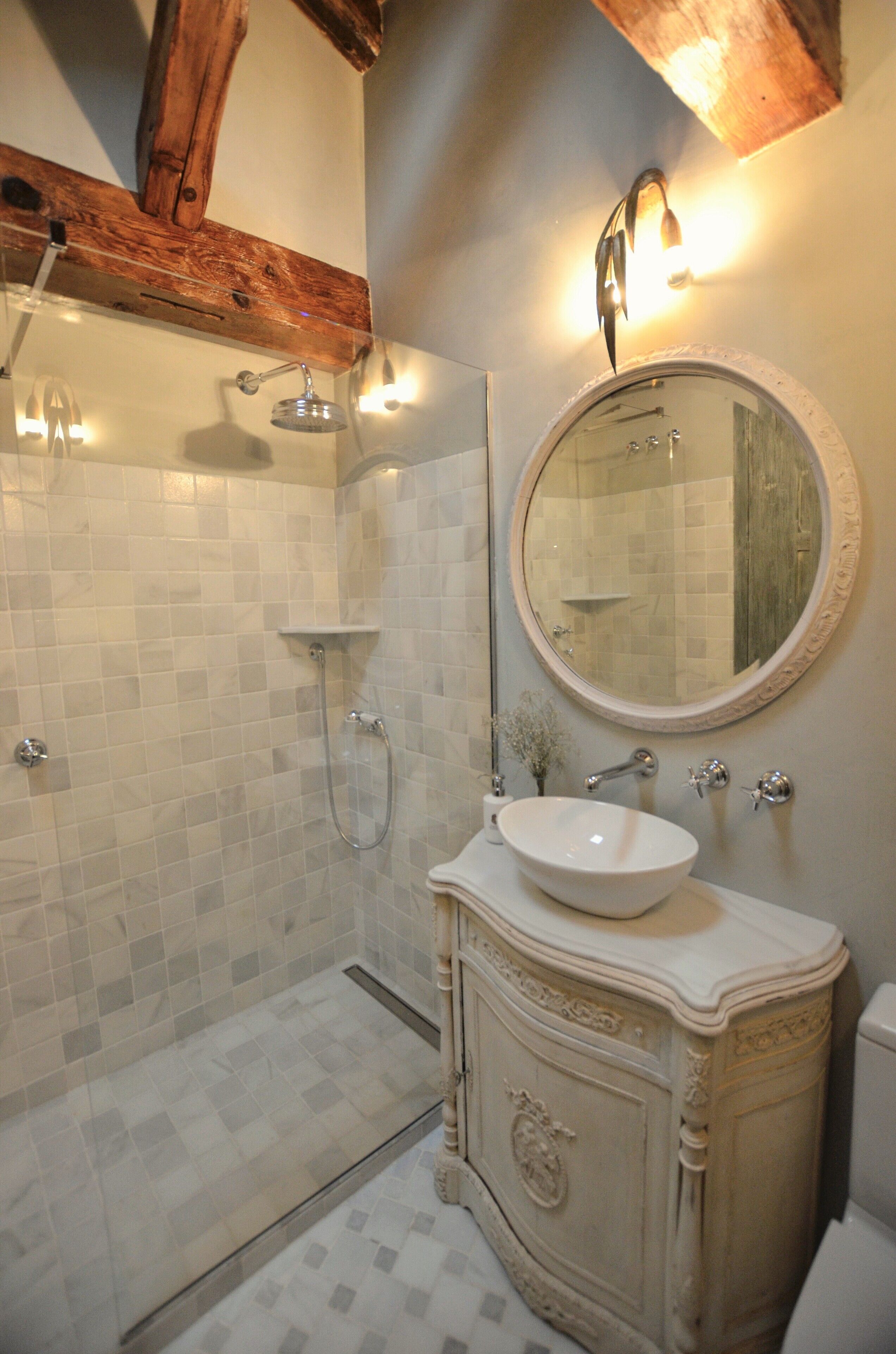 Un baño con ducha, lavamanos y espejo.
