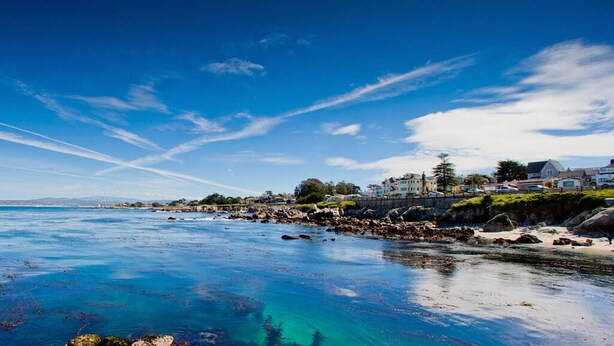 A coastal area with clear blue water, rocky shoreline, and residential buildings. - Gratitude Inn - Pacific Grove House - Downtown - Close to Beach (Pacific Grove)