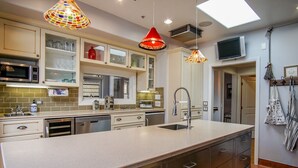 A modern kitchen with a large island, overhead pendant lights, and a microwave. - Gratitude Inn - Pacific Grove House - Downtown - Close to Beach (Pacific Grove)
