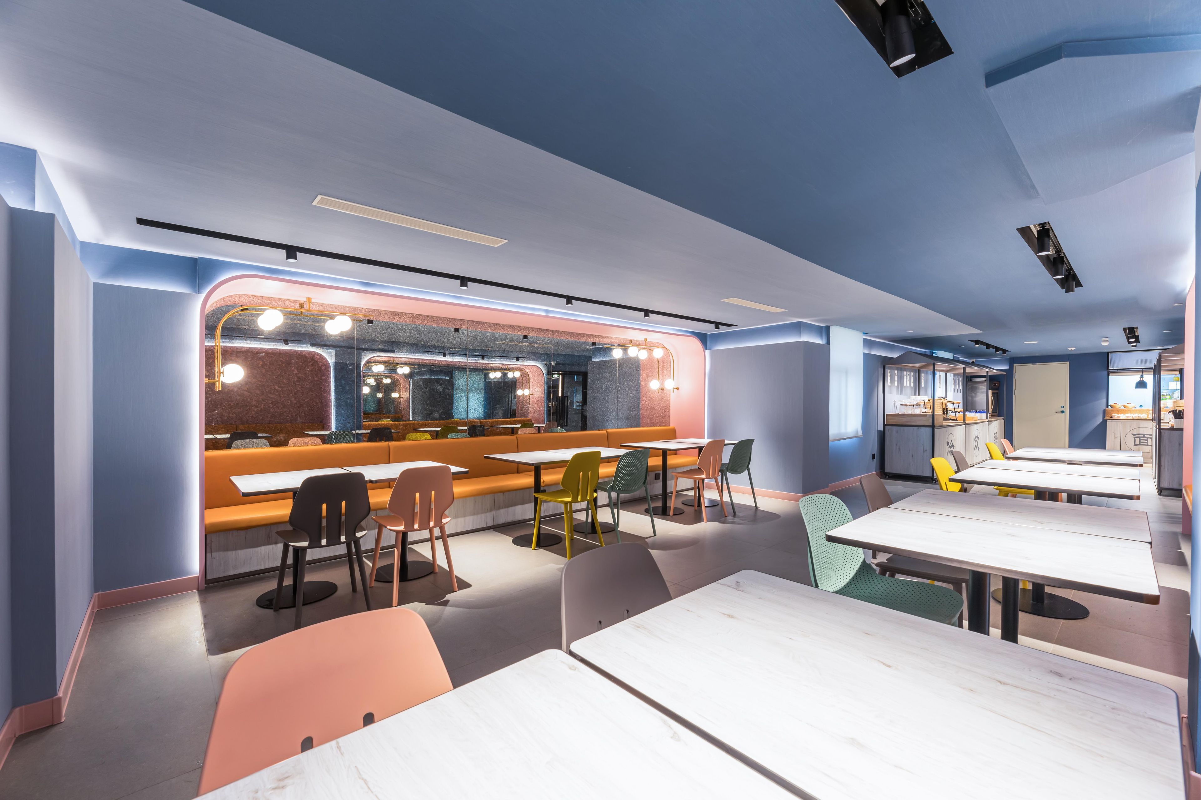 A modern restaurant interior with a bar area, seating arrangements, and a kitchen visible in the background.