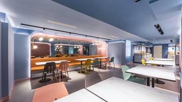 A modern restaurant interior with a bar area, seating arrangements, and a kitchen visible in the background.