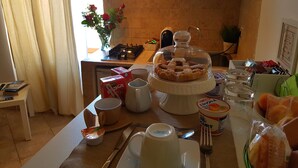 Una mesa de desayuno con diversos alimentos, incluyendo una pastelería cubierta, yogur y fruta.