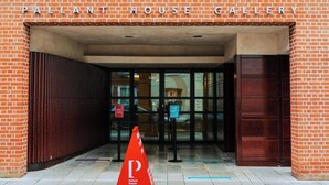 La entrada a la Galería Pallant House, con fachada de ladrillo, puertas de vidrio y un cono de estacionamiento rojo.
