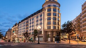 Un hotel de varios pisos con un diseño arquitectónico clásico, que destaca por una esquina curva y numerosas ventanas.