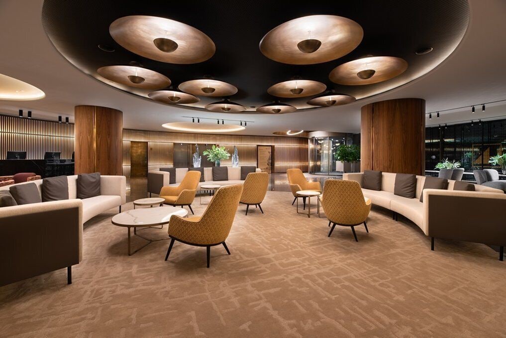 A modern lobby with a circular ceiling design, plush seating, and a reception area.