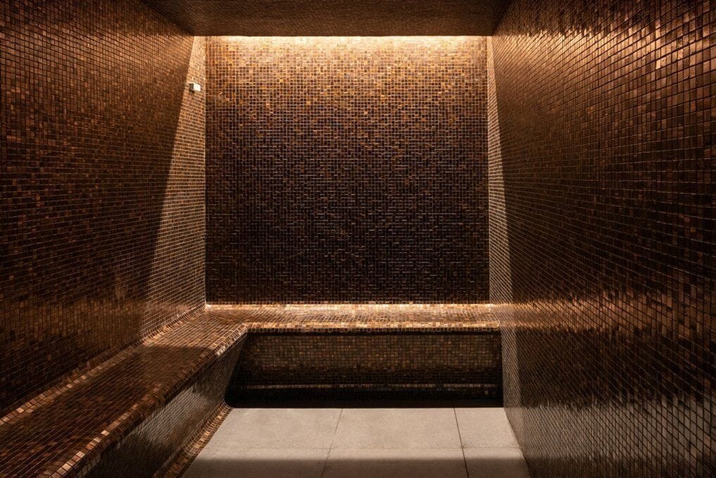 A narrow, enclosed space with a tiled floor and walls, featuring a small, open area at the end.