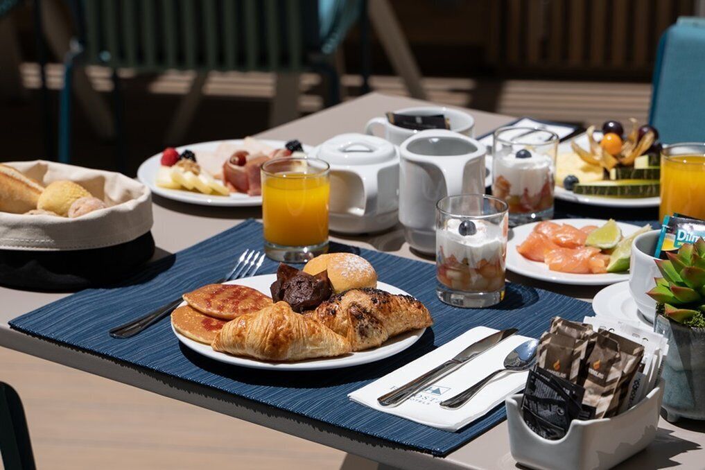 A breakfast table with croissants, fruit, and orange juice.