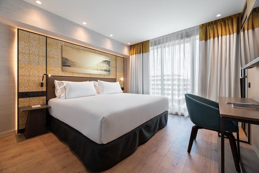 Una habitación de hotel con una cama grande, un escritorio y una silla.