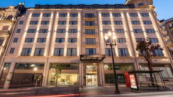 Un hotel grande de varios pisos con estilo arquitectónico clásico, que destaca por su entrada imponente y fachada bien iluminada.