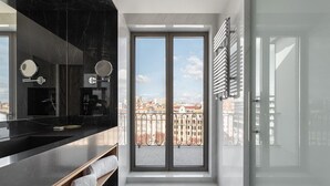 Un baño moderno con un ventanal grande, una encimera de mármol negro y una cabina de ducha de vidrio.