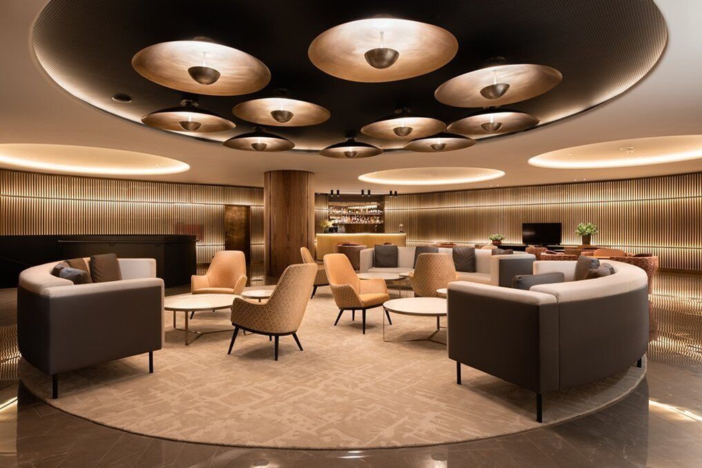 A modern lobby with a circular seating area, a bar, and a reception desk.