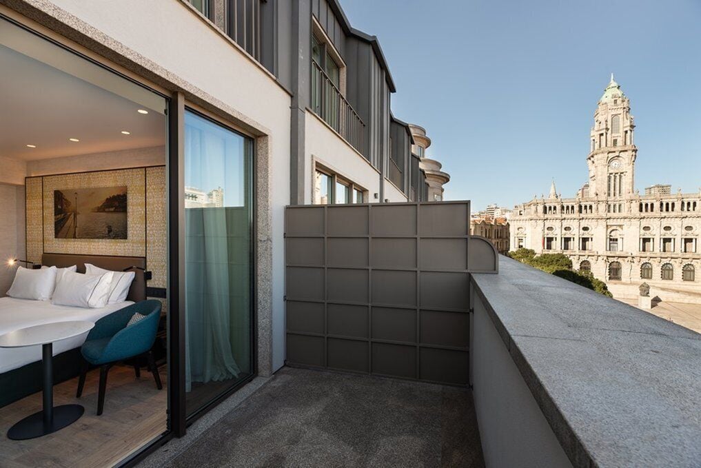 A balcony with a modern design, a dining area with a table and chairs, and a view of a historic building in the background.