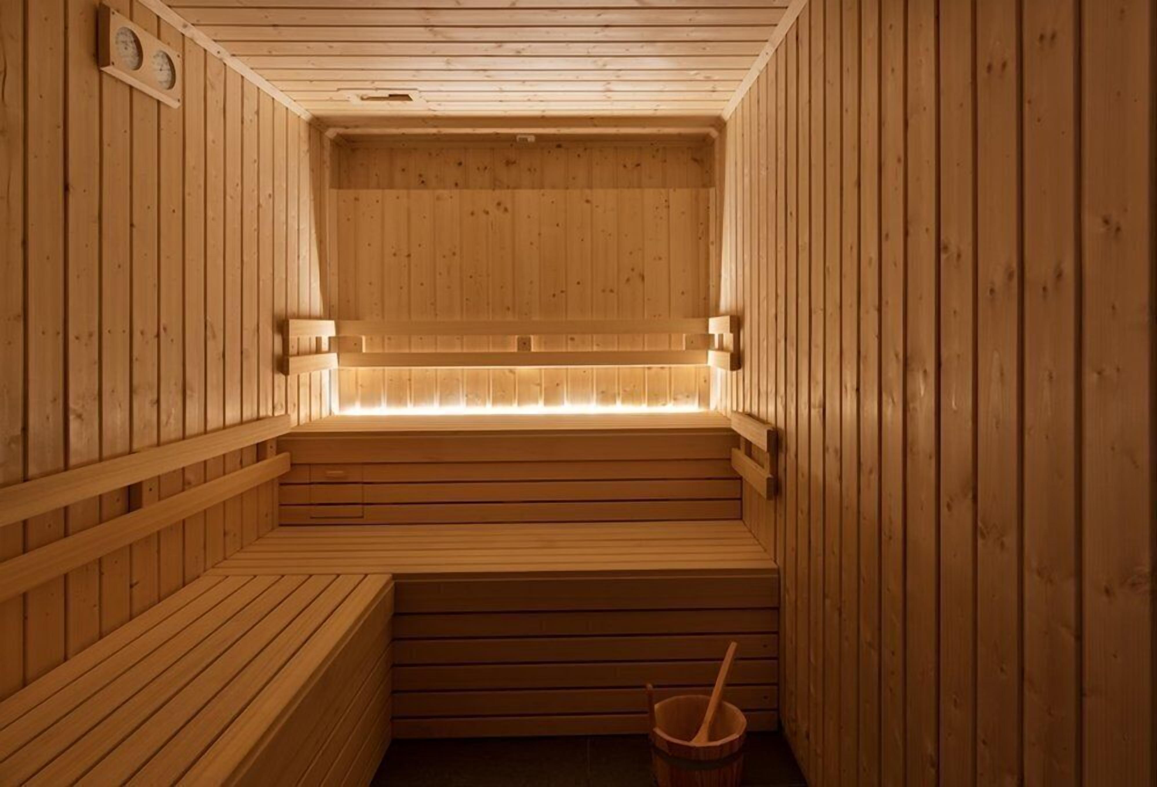 Un sauna en bois avec des bancs et un seau.