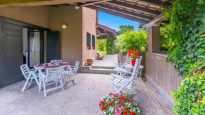 An outdoor patio with a pergola, white chairs, a table, and potted plants. - Residenza La Parusciola: 3 Beds Duplex With Shared Pool (Gignese)