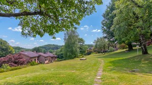 A grassy area with a stone path leading to a house with a dark roof. - Residenza La Parusciola: 3 Beds Duplex With Shared Pool (Gignese)