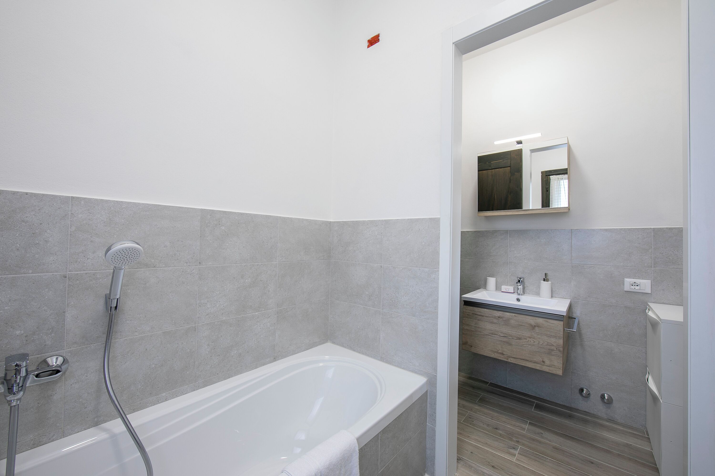 A modern bathroom with a bathtub, a shower, and a vanity with a mirror.