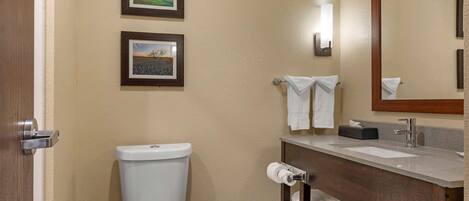 A bathroom with a toilet, sink, and two framed pictures on the wall.