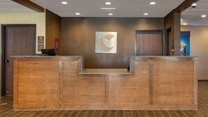 Un mostrador de recepción con acabado de madera, una obra de arte abstracto colgada en la pared y una pantalla digital.