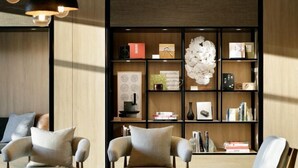 A modern living room with a wooden bookshelf, two armchairs, and pendant lighting.