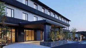 A modern hotel with a flat roof, large windows, and a covered entrance area.