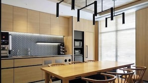 A modern kitchen with wooden cabinets, a herringbone backsplash, and a dining area with a wooden table and chairs.