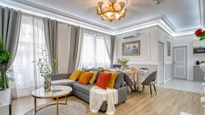 A spacious living room with a grey sofa, a round coffee table, and a dining area with a white table.