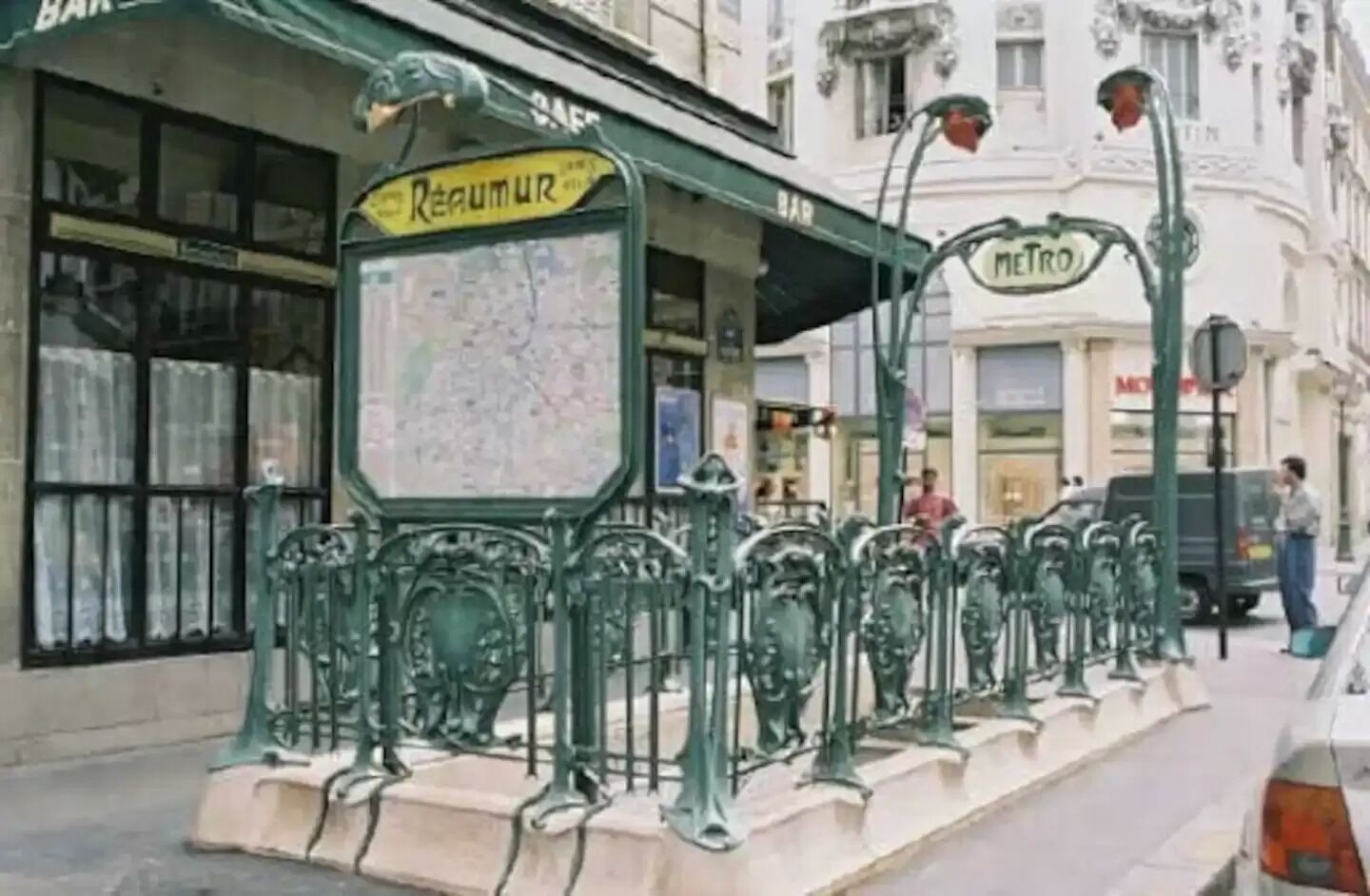 A street scene with a map sign, a metro sign, and a building with a bar.