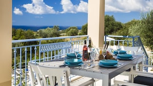 Mesa lista para comer con vista al mar y follaje.